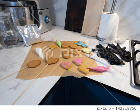 Assorted cookies with icing bags and a blue glove-shaped cookie cutter on the home kitchen counter Assorted cookies with icing bags and a blue glove-shaped cookie cutter on the home kitchen counter 142218756