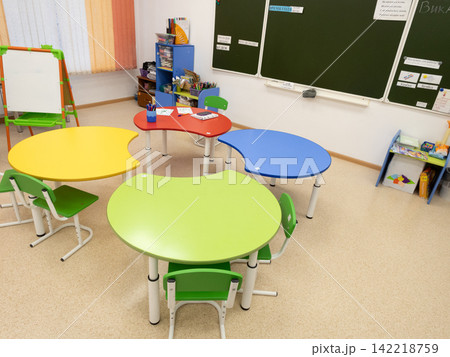 Bright colorful kindergarten classroom with curved activity tables ready for learning Bright colorful kindergarten classroom with curved activity tables ready for learning 142218759