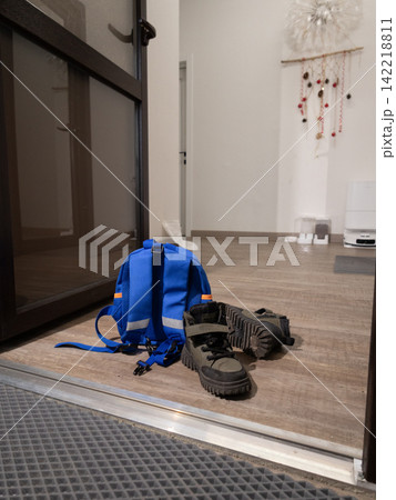 Blue backpack and black hiking boots rest on wooden entry floor Blue backpack and black hiking boots rest on wooden entry floor 142218811