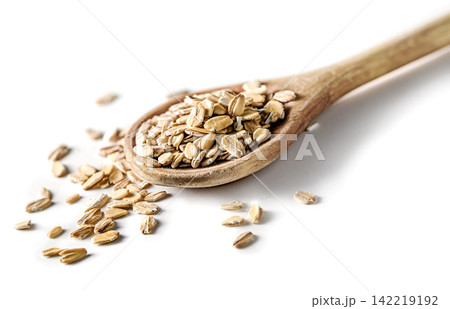 Wooden spoon heaped with raw oats and scattered oat flakes on white background closeup, Wooden spoon heaped with raw oats and scattered oat flakes on white background closeup, 142219192