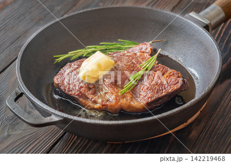 Pan seared ribeye steak with melting butter rosemary in rustic cast iron skillet Pan seared ribeye steak with melting butter rosemary in rustic cast iron skillet 142219468