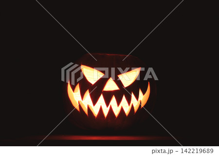Bright Halloween pumpkin face shining from the darkness Bright Halloween pumpkin face shining from the darkness 142219689