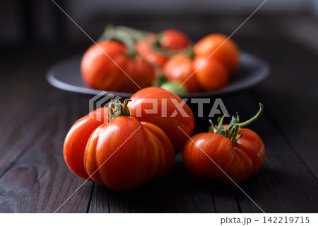 Red heirloom tomatoes on dark plate with shallow depth of field 142219715