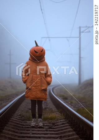 Pumpkin headed figure standing alone on railway tracks Pumpkin headed figure standing alone on railway tracks 142219717