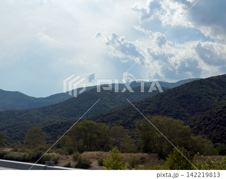 Mountain valley landscape beneath luminous dramatic cloudy sky Mountain valley landscape beneath luminous dramatic cloudy sky 142219813