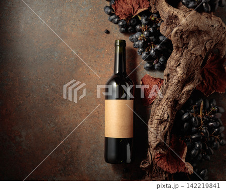 Bottle of red wine with blue grapes on a rusty background. Bottle of red wine with blue grapes on a rusty background. 142219841