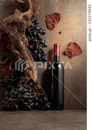 Bottle of red wine with blue grapes on a rusty background. Bottle of red wine with blue grapes on a rusty background. 142219842