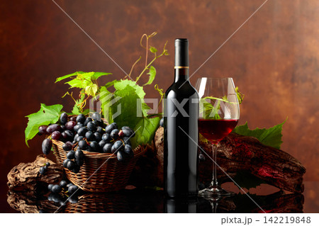 Glass and bottle of red wine with blue grapes and vine branches. Glass and bottle of red wine with blue grapes and vine branches. 142219848