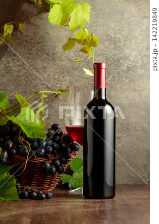 Glass and bottle of red wine with blue grapes and vine branches. Glass and bottle of red wine with blue grapes and vine branches. 142219849