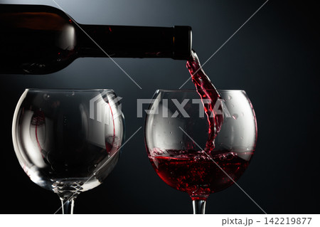 Pouring red wine into a wine glass. 142219877