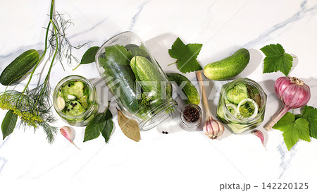 Cucumbers with dill, garlic, horseradish, pickling leaves, and pickled cucumbers in jars on the kitchen counter. Harvest concept. Recipe and ingredients for homemade pickles. Home canning Cucumbers with dill, garlic, horseradish, pickling leaves, and pickled cucumbers in jars on the kitchen counter. Harvest concept. Recipe and ingredients for homemade pickles. Home canning 142220125