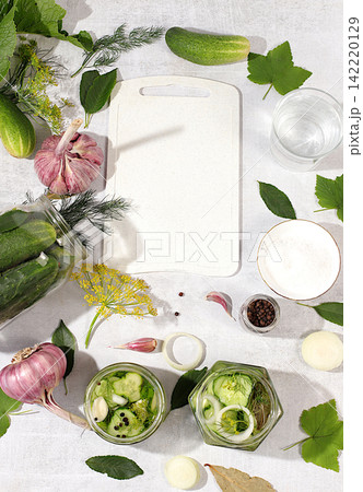 Recipe and ingredients for homemade pickles. Cucumbers with dill, garlic, horseradish, pickling leaves, and pickled cucumbers in jars on the kitchen counter. Harvest concept. Home canning 142220129