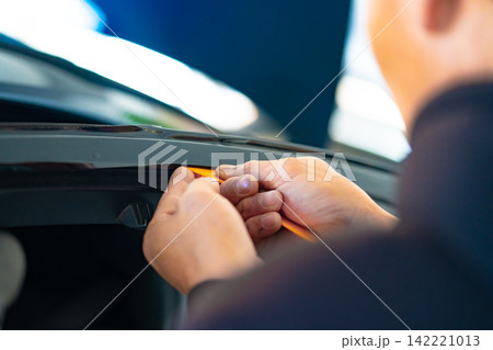 A car wrapping specialist applies a polyurethane film to the car. Detailer PPF A car wrapping specialist applies a polyurethane film to the car. Detailer PPF 142221013