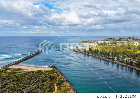 Aerial view of the breakwalls at Port Macquarie with the Hastings River, caravan park and surrounding coastal landscape, showing the river entrance where the waterway meets the Pacific Ocean Aerial view of the breakwalls at Port Macquarie with the Hastings River, caravan park and surrounding coastal landscape, showing the river entrance where the waterway meets the Pacific Ocean 142221184