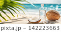 Refreshing Coconut Water Bottles on a Pristine Sandy Beach with Palm Leaves 142223663