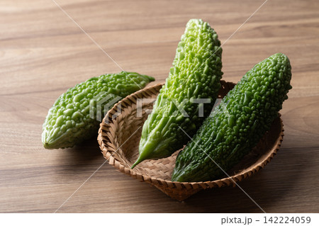 Fresh bitter gourd or bitter melon in a basket on a wooden background 142224059
