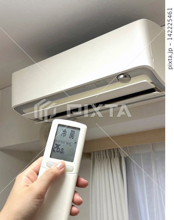 エアコンの用リモコンを操作して冷房をつける女性の手元 エアコンの用リモコンを操作して冷房をつける女性の手元 142225461