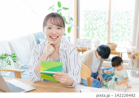 通帳を見て笑顔の女性 142226492