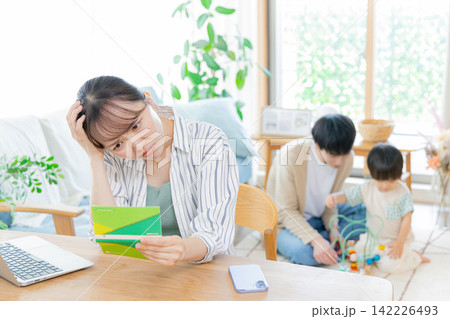 通帳を見て悩むお母さん 通帳を見て悩むお母さん 142226493