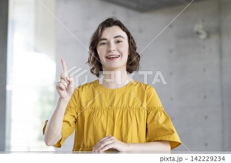 人差し指を立てながらカメラ目線で話す笑顔の外国人女性 人差し指を立てながらカメラ目線で話す笑顔の外国人女性 142229234