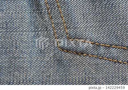 Blue Denim Fabric With Angular Golden Seam Stitching Filling Frame, Showing Diagonal Twill Weave Blue Denim Fabric With Angular Golden Seam Stitching Filling Frame, Showing Diagonal Twill Weave 142229459