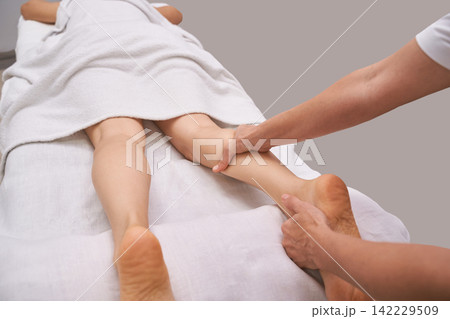 Leg Massage Therapist Working On Lower Leg And Foot During Treatment On Spa Table With White Linens 142229509