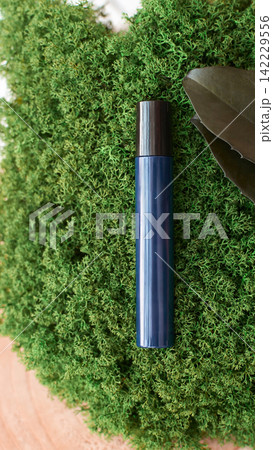 Blue Slender Bottle Positioned Vertically On Dense Green Moss With Brown Leaf Accent Top Black Cap 142229556