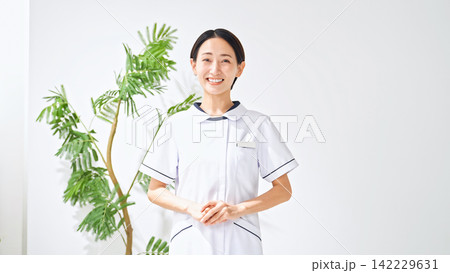 笑顔の白衣の女性。看護師、介護士、病院、クリニック、案内、接客、元気、満足、医療事務、受付、資格 笑顔の白衣の女性。看護師、介護士、病院、クリニック、案内、接客、元気、満足、医療事務、受付、資格 142229631