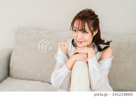 自宅のソファでリラックスする中年女性 自宅のソファでリラックスする中年女性 142229669