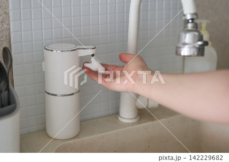 Hand Catching Foam Dispensed By Automatic Soap Dispenser At Kitchen Sink Countertop Next To Faucet Hand Catching Foam Dispensed By Automatic Soap Dispenser At Kitchen Sink Countertop Next To Faucet 142229682