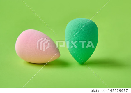 Makeup Sponge Pair Resting On Seamless Green Backdrop Studio Surface With Pastel Pink And Mint 142229977