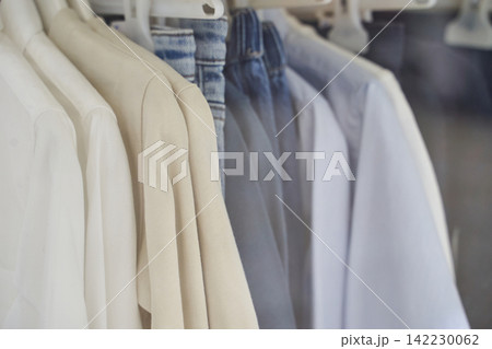 Light Colored Shirts And Denim Jeans Hanging On Rack In Retail Clothing Store Display Arranged Light Colored Shirts And Denim Jeans Hanging On Rack In Retail Clothing Store Display Arranged 142230062