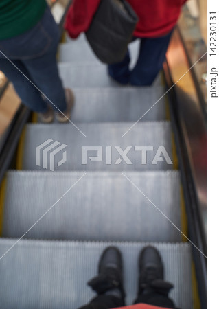 People Riding Escalator Viewed Above Showing Feet On Metal Treads Steps And Moving Handrail People Riding Escalator Viewed Above Showing Feet On Metal Treads Steps And Moving Handrail 142230131