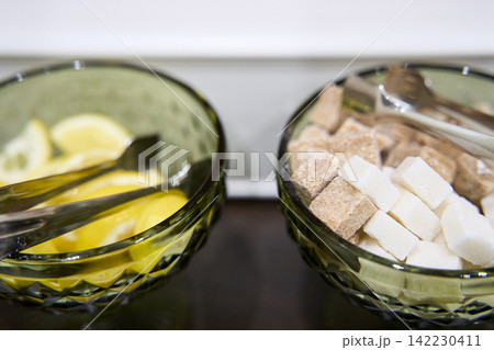 Two Green Cut Glass Bowls Containing Lemon Slices And Mixed Sugar Cubes With Metal Tongs Placed Two Green Cut Glass Bowls Containing Lemon Slices And Mixed Sugar Cubes With Metal Tongs Placed 142230411