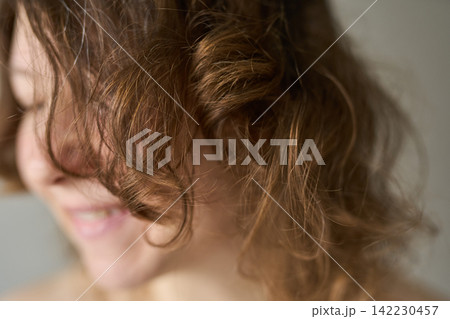Woman Smiling With Messy Curly Brown Hair Covering Face In Closeup Indoor Portrait With Soft Woman Smiling With Messy Curly Brown Hair Covering Face In Closeup Indoor Portrait With Soft 142230457