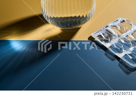 Glass Vase Casting Shadow Beside Empty Blister Pack On Two Color Tabletop Under Directional 142230731