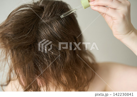 Person Tilting Head Forward Applying Scalp Oil With Dropper To Roots Exposing Scalp And Textured Person Tilting Head Forward Applying Scalp Oil With Dropper To Roots Exposing Scalp And Textured 142230841