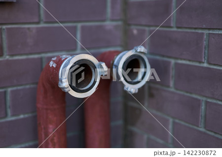 Red Dual Pipes With Open Coupling Connectors Against Brick Wall Closeup Showing Metal Fittings 142230872