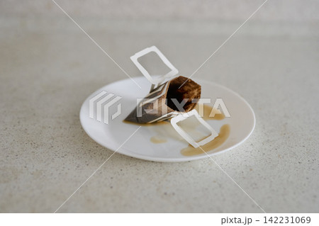Tea Bag Resting White Plate On Speckled Countertop Close Up Minimal Tabletop Scene With Brown Tea Tea Bag Resting White Plate On Speckled Countertop Close Up Minimal Tabletop Scene With Brown Tea 142231069