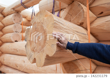 The construction site of a wooden house. Traditional log cabin built from wood logs on sunny summer day. Cottage house design The construction site of a wooden house. Traditional log cabin built from wood logs on sunny summer day. Cottage house design 142231179