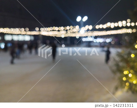 Outdoor Ice Rink With Blurred Skaters Moving Under String Lights And Illuminated Decorations 142231311