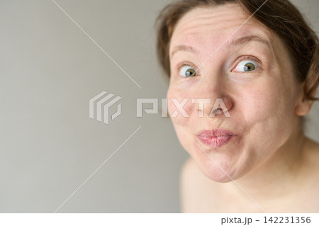 Woman Puckering Lips And Making Playful Kiss Face In Plain Gray Background Closeup Portrait Bare 142231356