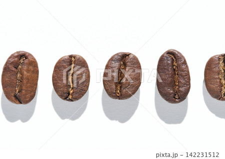 Coffee Bean Aligned In Single Horizontal Row Casting Distinct Shadows On White Studio Background Coffee Bean Aligned In Single Horizontal Row Casting Distinct Shadows On White Studio Background 142231512