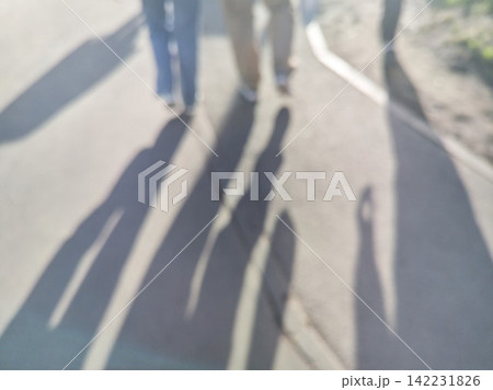 Multiple Pedestrians Casting Long Elongated Shadows While Walking On Sunlit Pavement In Outdoor Multiple Pedestrians Casting Long Elongated Shadows While Walking On Sunlit Pavement In Outdoor 142231826