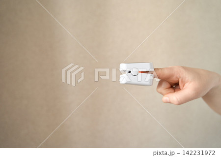 Single hand holding pulse oximeter device isolated showing portable healthcare monitoring equipment Single hand holding pulse oximeter device isolated showing portable healthcare monitoring equipment 142231972