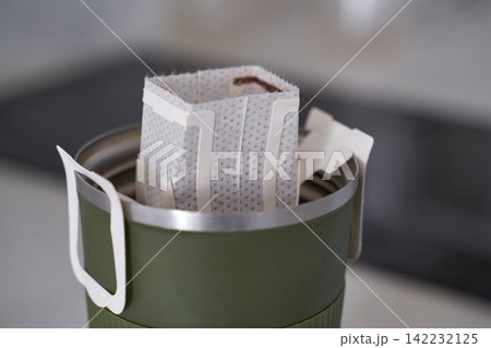 Single Use Drip Coffee Filter Suspended Over Green Travel Mug Ready For Pouring In Kitchen Counter Single Use Drip Coffee Filter Suspended Over Green Travel Mug Ready For Pouring In Kitchen Counter 142232125