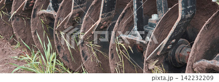 Disc Harrow Blades Coated With Wet Soil While Cutting Through Grassy Field During Tilling Operation Disc Harrow Blades Coated With Wet Soil While Cutting Through Grassy Field During Tilling Operation 142232209