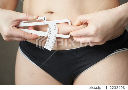 Female measuring body fat with caliper health, fitness, nutrition, self-assessment, wellness, body Female measuring body fat with caliper health, fitness, nutrition, self-assessment, wellness, body 142232408