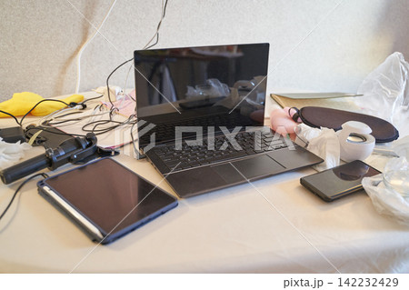Messy Workspace With Laptop, Tablet, And Smartphone On Cluttered Table In Home Office Setting Messy Workspace With Laptop, Tablet, And Smartphone On Cluttered Table In Home Office Setting 142232429