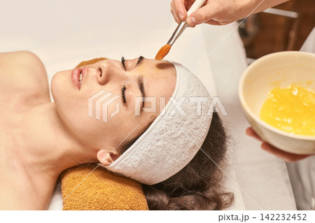 Young Caucasian Female Relaxing During Spa Facial Treatment With Rejuvenating Face Mask Application Young Caucasian Female Relaxing During Spa Facial Treatment With Rejuvenating Face Mask Application 142232452